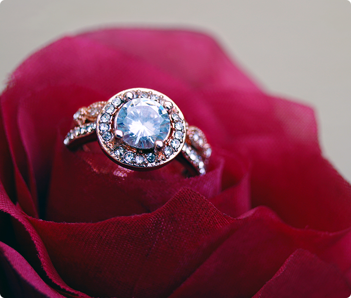 A diamond ring is sitting in the middle of a rose.