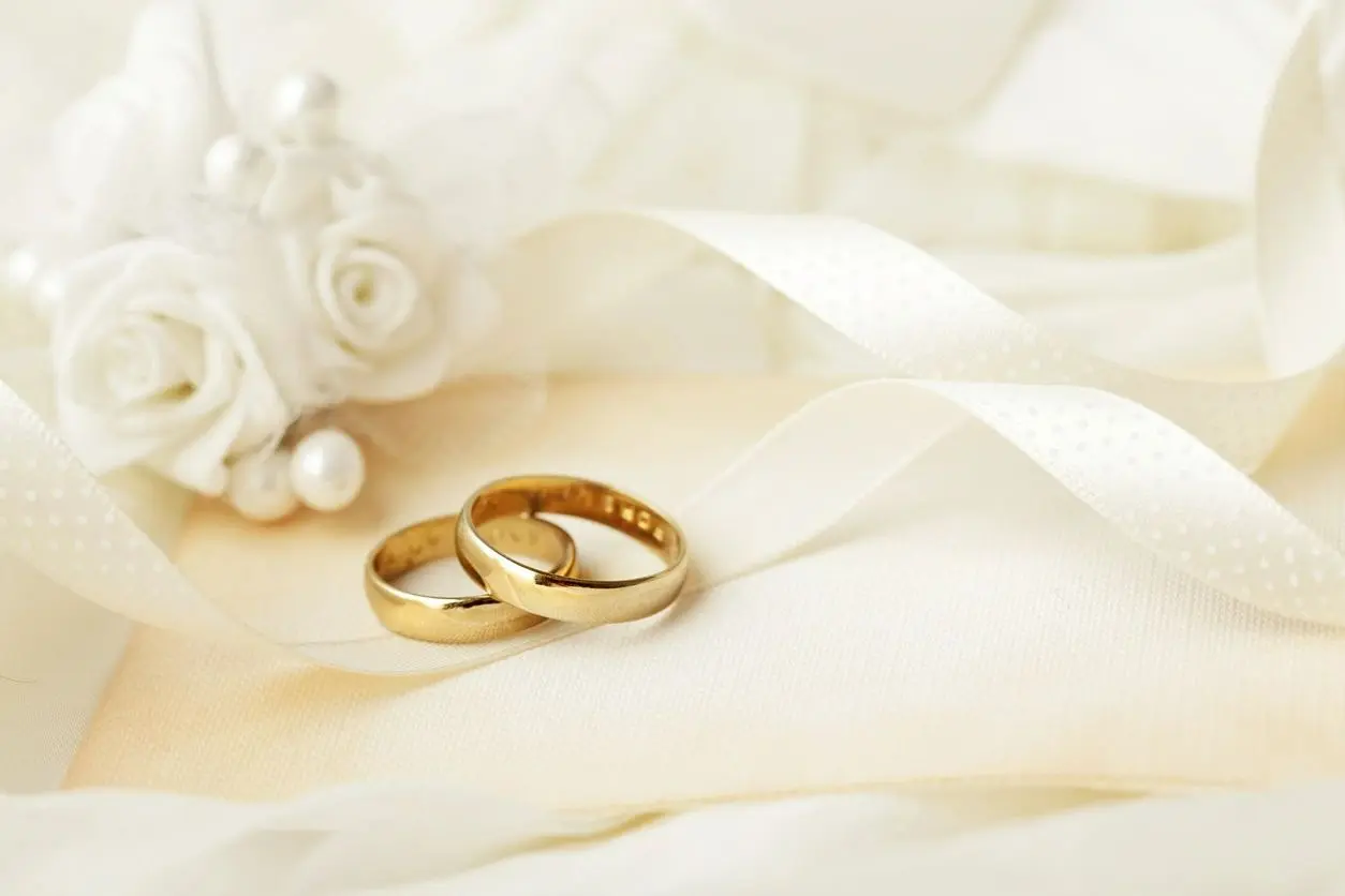 Two wedding rings sitting on top of a white cloth.