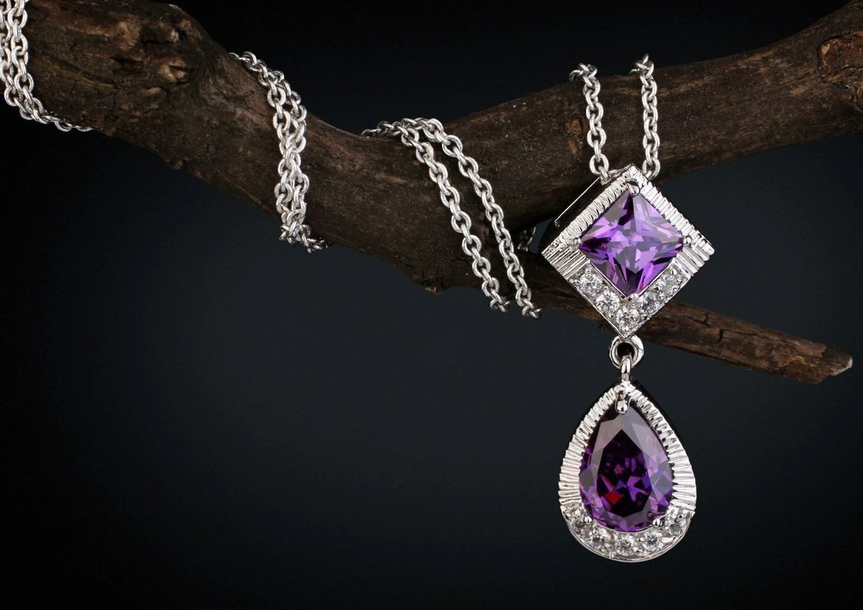 A necklace with a purple stone hanging from it.