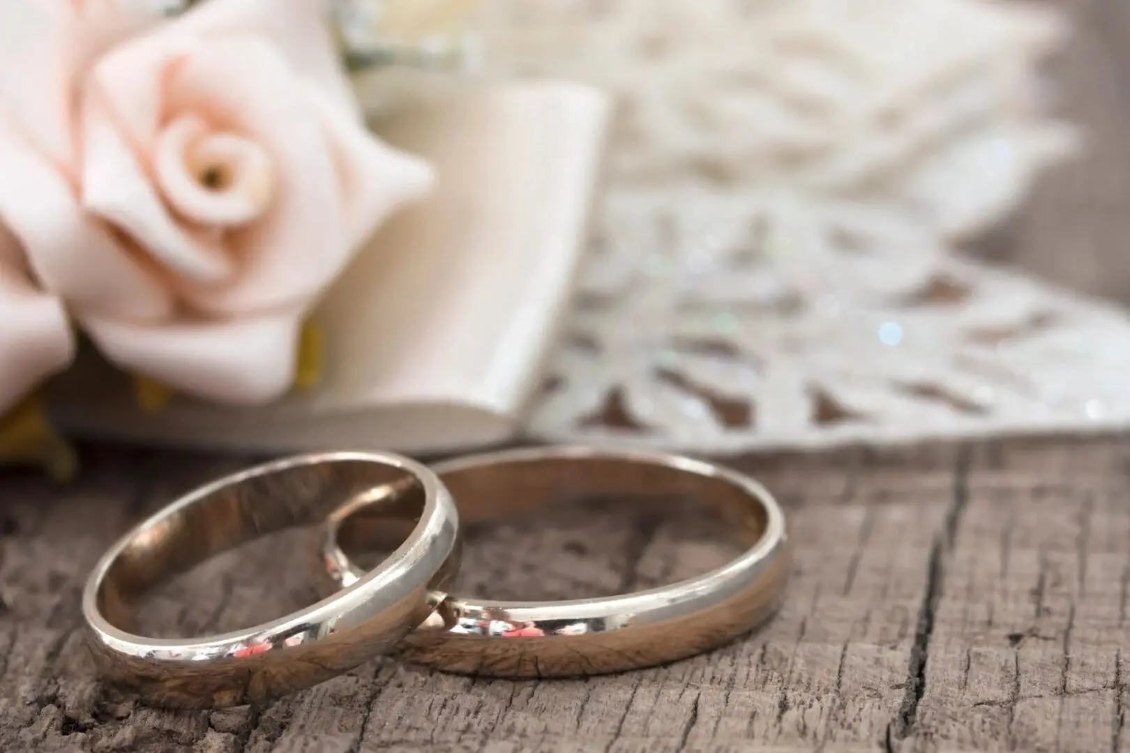 Two wedding rings sitting on top of a wooden table.