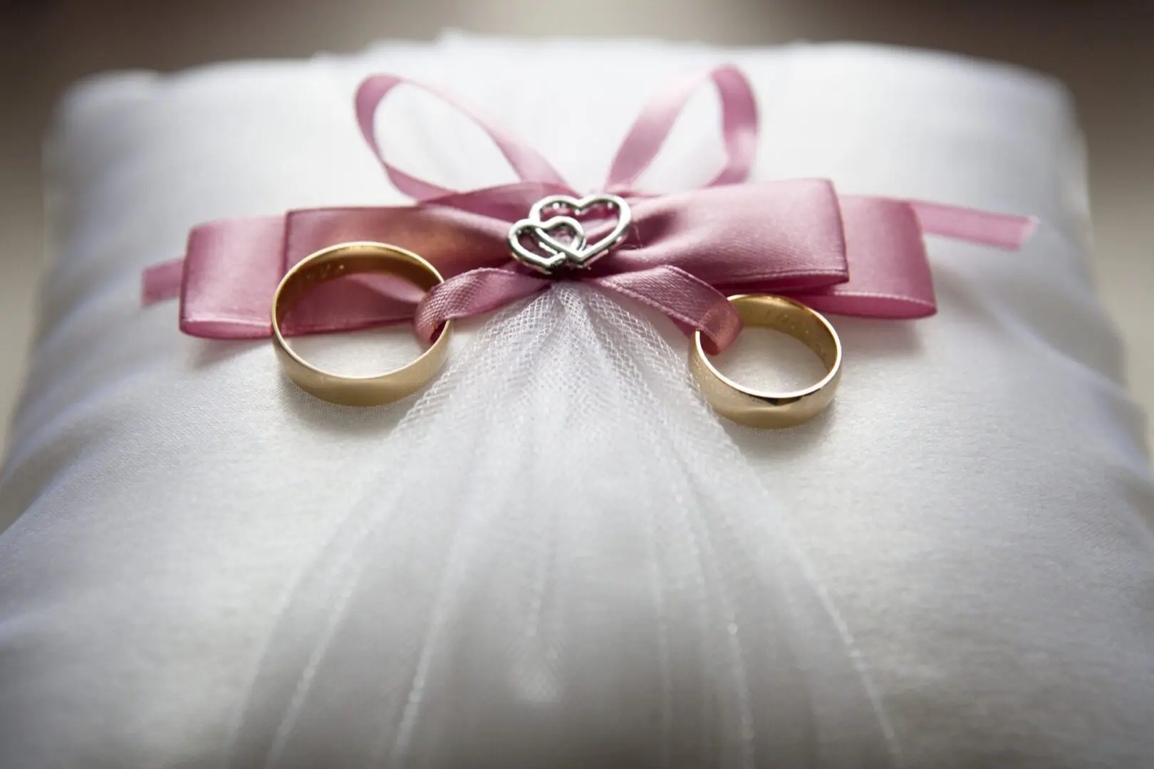Two wedding rings sitting on top of a white pillow.