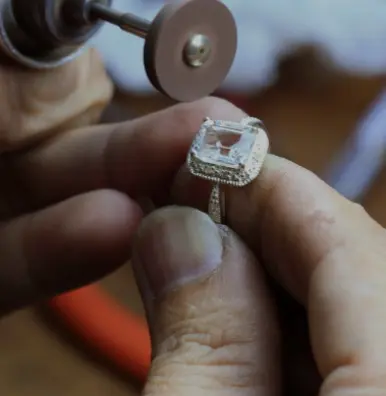 A person working on a ring with a diamond.