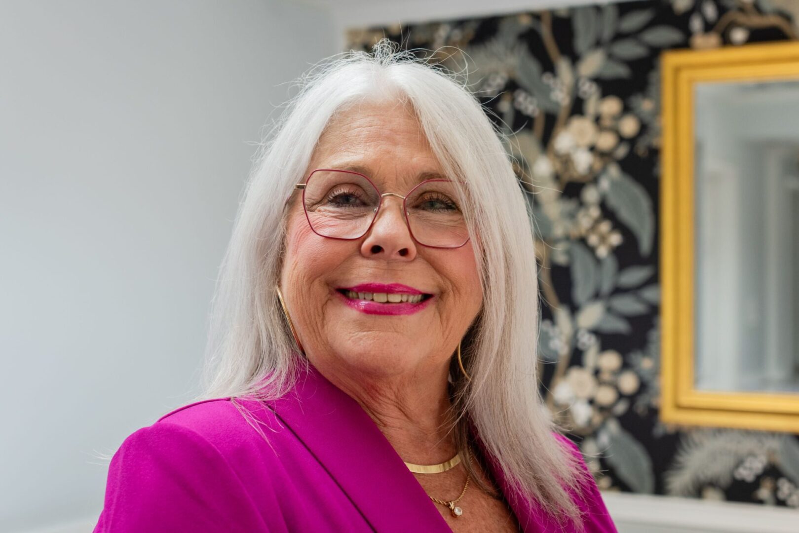 A woman with white hair and wearing glasses.