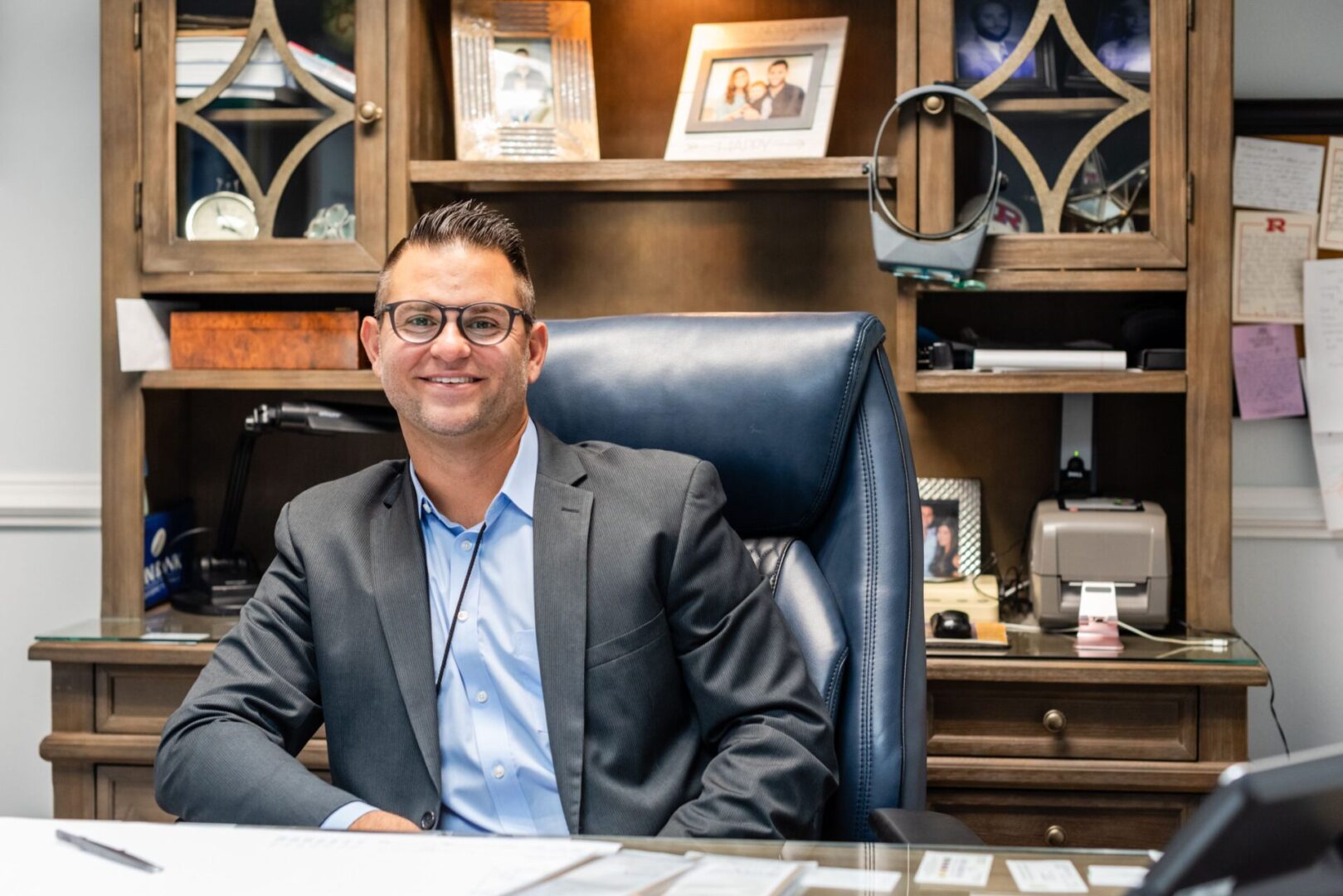 A man sitting at his desk in front of a bookshelf.